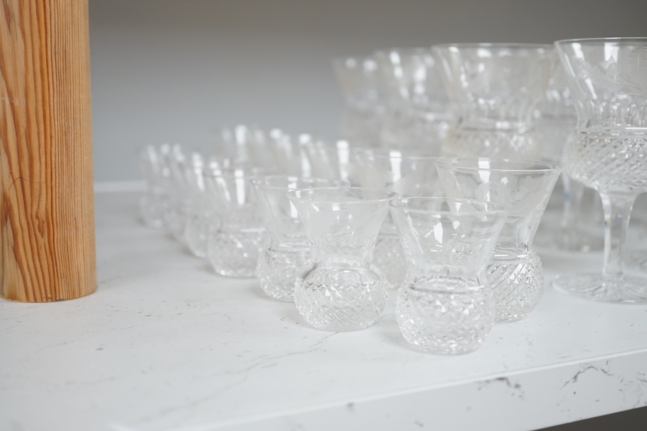 A set of twenty four Edinburgh cut glass thistle glasses and thirteen assorted smaller examples, largest 12cm high. Condition - mostly good